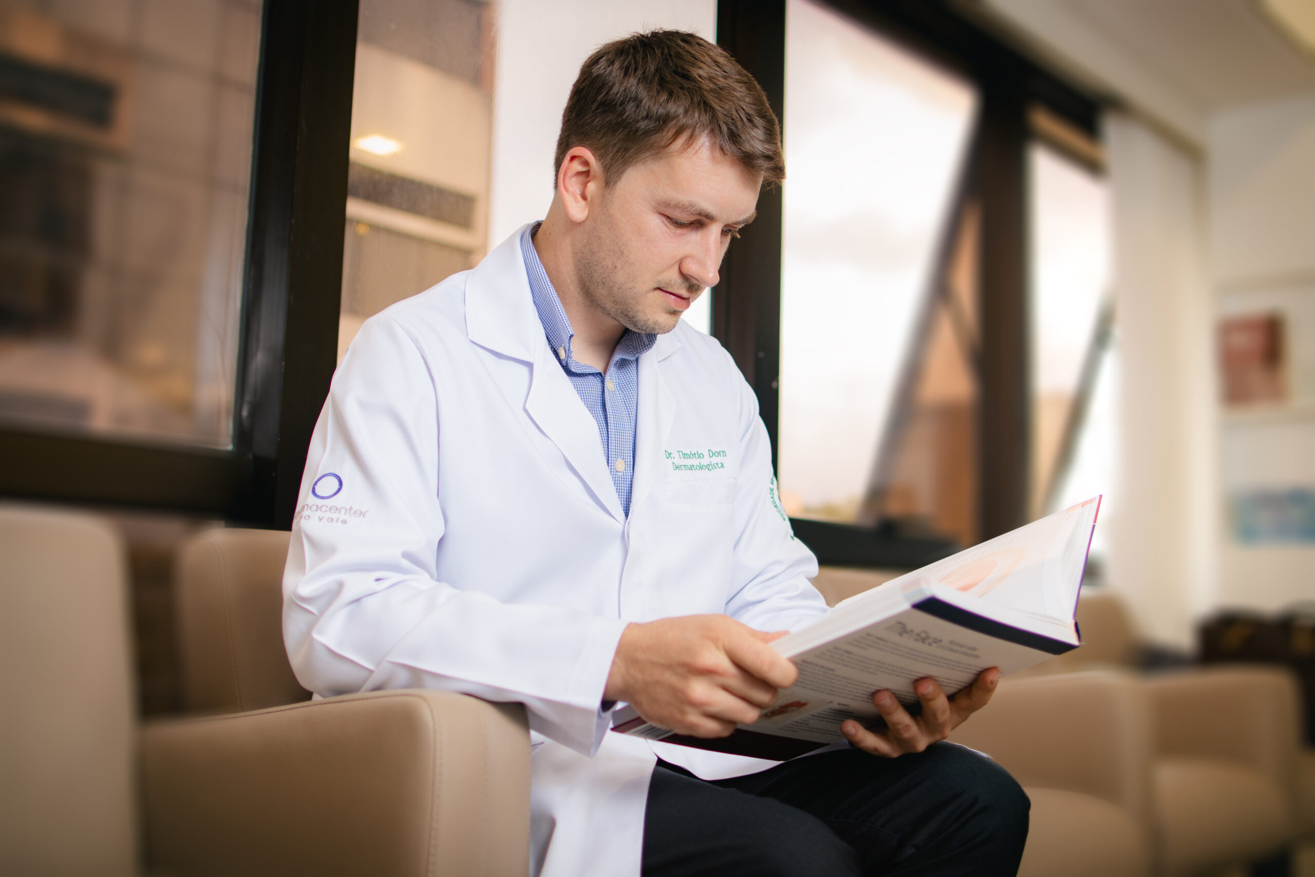 Dermatologista consulta literatura científica sobre cirurgia de Mohs e reconstrução facial para atualização e planejamento do tratamento do câncer de pele.