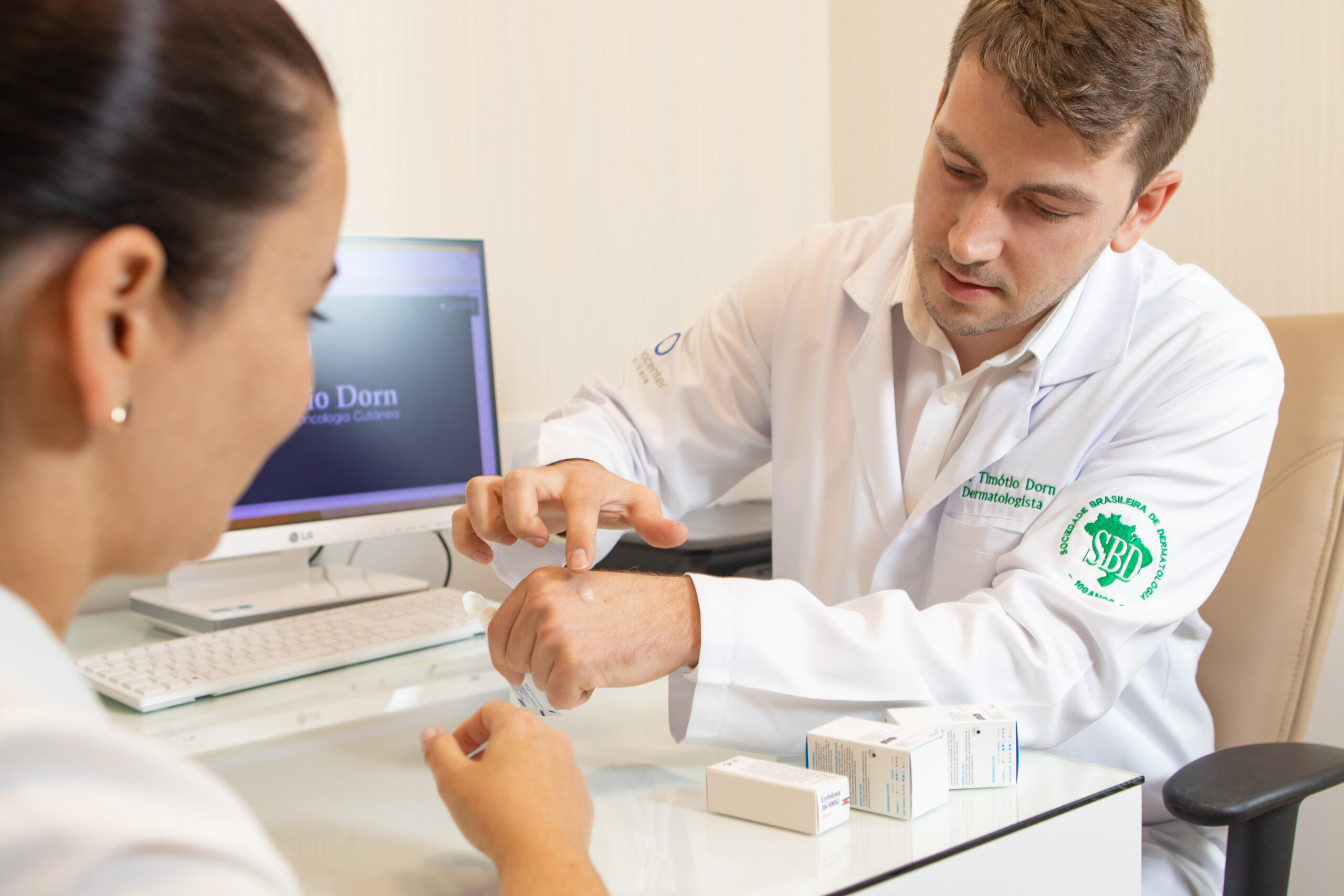 Dermatologista orienta paciente sobre cuidados com a pele e aplicação de tratamento tópico durante consulta para cirurgia de Mohs.